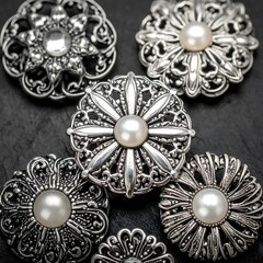 Close-up of intricately designed silver brooches with central pearls, arranged on a dark, textured surface, showcasing detailed craftsmanship