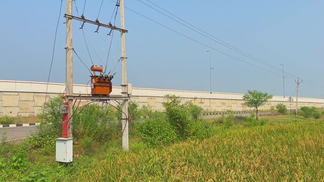 A panning shot that stops at a small electric transformer installed near farmland, used to supply electricity to farmers for irrigation and other uses.