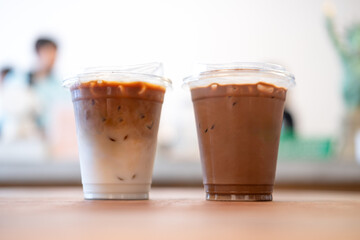 Two plastic takeaway cups of iced coffee latte and iced mocha on the table in the coffee shop
