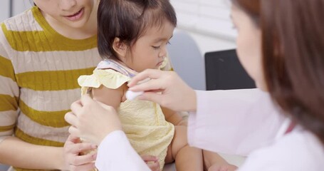 Asian toddler receiving vaccination injection from female pediatrician, mother holding child during slowmotion clinic moment, emotional family care showing protection, tenderness, healthcare - Powered by Adobe