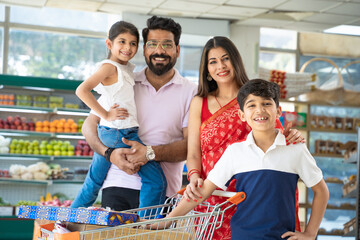 Indian family standing together at grocery shop.