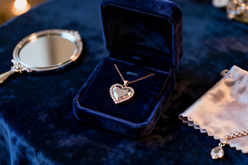 A stunning heart-shaped diamond pendant necklace is displayed inside an open dark blue velvet jewelry box, placed on a luxurious velvet surface, suggesting a proposal or gift.