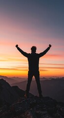 Fototapeta premium Silhouette of a man standing on top of a mountain and raising his hands up