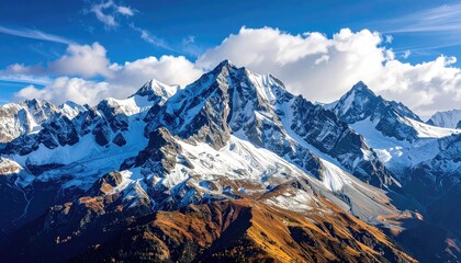 Vast Snow Capped Mountains Under a Vibrant Blue Sky with Wispy Clouds and Autumn Foliage Below