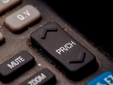 A remote control with channel and function buttons show signs of age and use on the surface.