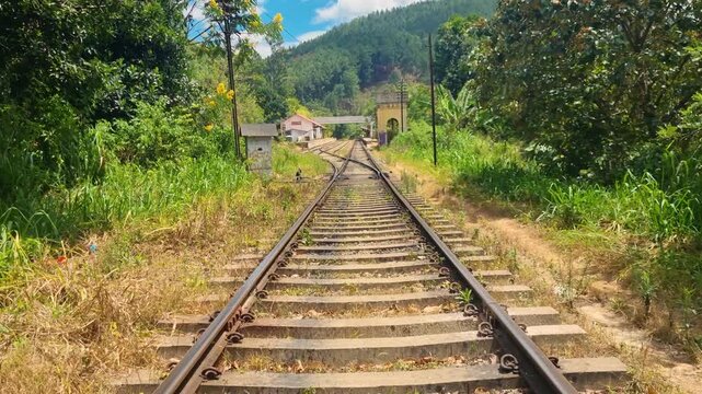 Forward-moving shot along the iconic Badulla&ndash;Colombo railway to Ella, Sri Lanka, tracks cutting through lush tropical jungle under a clear blue sky, no people in view
