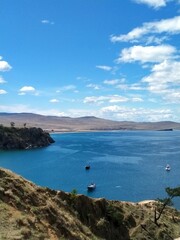 Turquoise bay and boats by the rocky shore under a clear sky. A calm water surface, a summer landscape and a sense of relaxation.