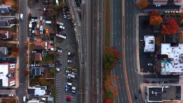 A top down, aerial view of Sunrise Highway running parallel to the Long Island Railroad's elevated train tracks as a train passes by. Taken on Long Island on a cloudy day.