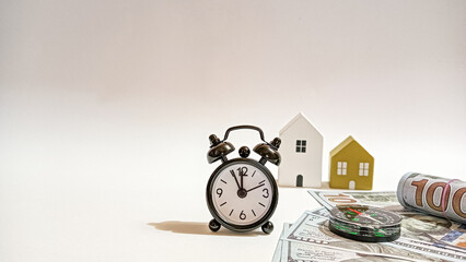 A vintage clock, compass, and model houses with dollar bills symbolize the importance of time, direction, and wise planning in achieving financial stability and property investment success.