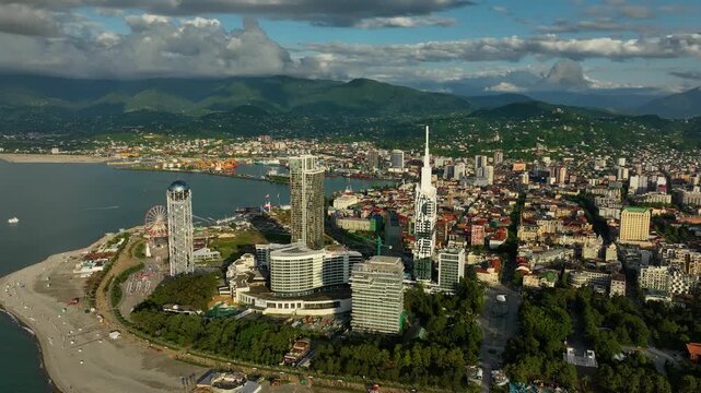 A panoramic drone view showing Batumi&rsquo;s skyline, sandy beach, and lush green hills in the distance. The mix of city energy, seaside relaxation