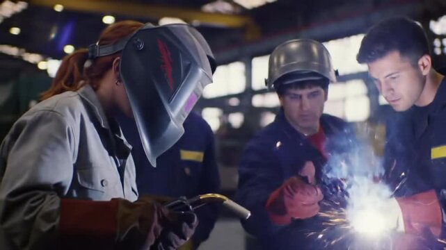 Three welders in a workshop one is welding