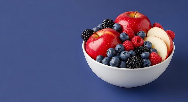 a white ceramic bowl filled with fresh fruits like apples and berries