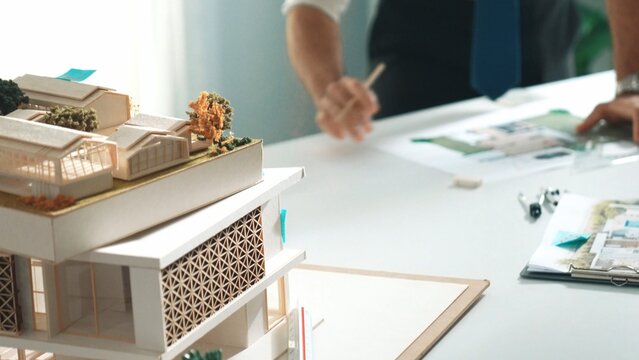 Close up of smart business team hand working together to plan design while looking at project plan from tablet and discussing about blueprint and building construction at meeting table. Alimentation.