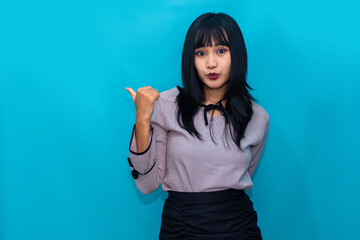 Fototapeta premium A woman gestures with her thumb toward herself while looking surprised. Ideal for self-expression, identity, and influencer-style content.