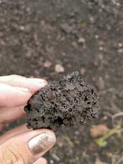 A porous fragment of frozen lava held by fingers. Macro photography for topics such as geology, minerals, volcanoes, science, and education.