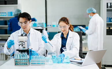 Team of scientists analyzing blue liquid samples in a modern lab, showcasing biotechnology, chemistry, and medical research innovation.