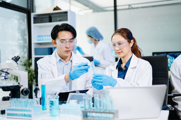 Fototapeta premium Scientists collaborating in a modern lab with microscopes and blue liquids, representing biotechnology, chemistry, and medical research innovation.