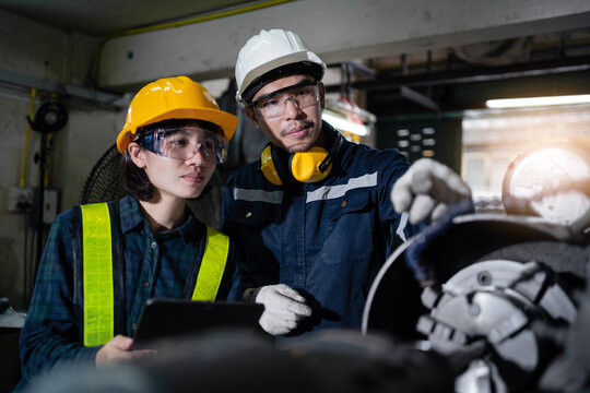 Two workers wearing safety gear and looking at a tablet