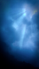 Floating beneath the wild ocean surface. Underwater photography. Below the wild surface- Rays of light through the waves. 