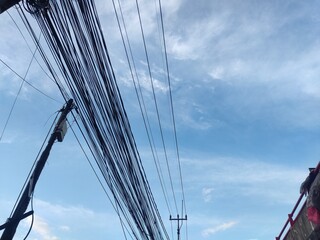 a string of black electrical cables on the side of the highway with a bright blue sky in the background
