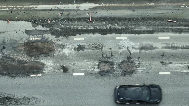 From above, the cracked and damaged road surface shows visible signs of wear, signaling issues in public investment, safety, environmental management, infrastructure resilience, and city planning.
