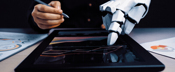 A captivating scene of a robotic arm and a human hand working together on a touchscreen device, demonstrating advanced technology in data analysis and visualization.Noogenesis