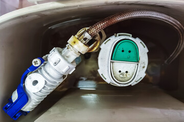Old broken toilet water tank. Toilet tank interior with fill valve and flush valve components. Residential home bathroom toilet tank plumbing repair. Replace old leaking restroom lavatory flush valve