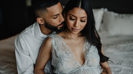 A couple shares a tender moment in their bedroom, capturing their excitement for the upcoming arrival of their baby. Soft light enhances their connection and intimacy