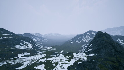 A breathtaking view of towering mountains and lush valleys under a soft, cloudy sky. Snow blankets parts of the landscape, creating a stunning contrast with the greenery below.