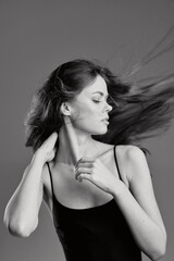 Naklejka premium Black and white portrait of a young woman with flowing hair wearing a sleeveless top in calm expression