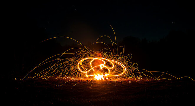 Long exposure steel wool fire spinning at night under starry sky