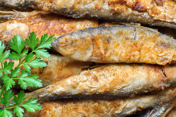 Fried capelin fish with a sprig of parsley. Fresh fried fish