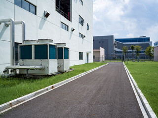 Fototapeta premium Industrial air conditioning units by white building, with green grass