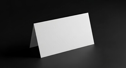 White card is folded  standing on a black surface angled to the right