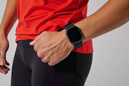Close-up of a person in red athletic wear checking their black smartwatch during a workout. Concept of fitness tracking, wearable technology, and monitoring health or activity goals