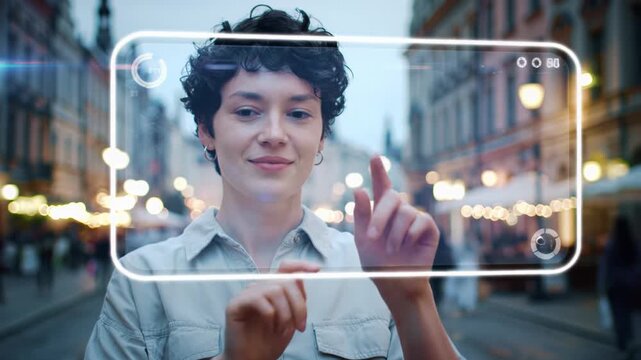 Young caucasian woman with curly dark hair elegantly interacts with a glowing sapphire blue holographic screen on a cobblestone urban street at dusk, cinematic neo-futuristic technology interaction