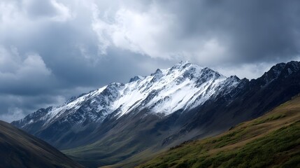 Snow capped mountain peaks rise majestically under a dramatic cloudy sky