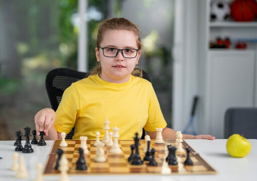 Kid playing chess at home. Child thinking over chess move. Kids learn strategy with chess. Kid concentrating on chessboard. Teen studying chess game. Thoughtful child playing board game at desk.