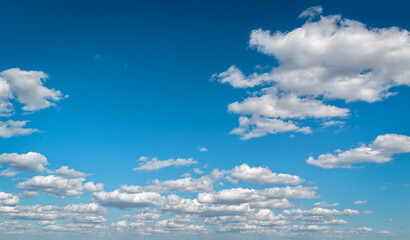 A clear blue sky adorned with fluffy white clouds. Calm serene cloud background.