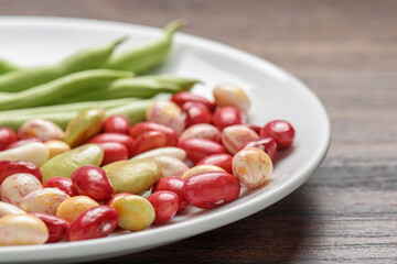 Colorful beans of different varieties and sizes on white plate