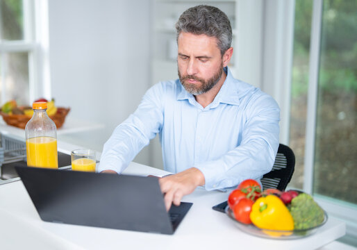 Healthy nutrition mature man. Aged man with healthy products at kitchen. Handsome Senior Man Eating Tasty Meal In Kitchen At Home. Elderly Man at Table Enjoying Delicious Food. Morning breakfast. - Powered by Adobe