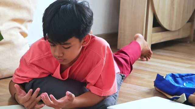 Young asian boy engrossed in reading or learning on floor focused and studious