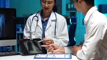 female doctor consulting with patient concerned and showing chest X-ray on digital tablet during health checkup in hospital office. - Powered by Adobe
