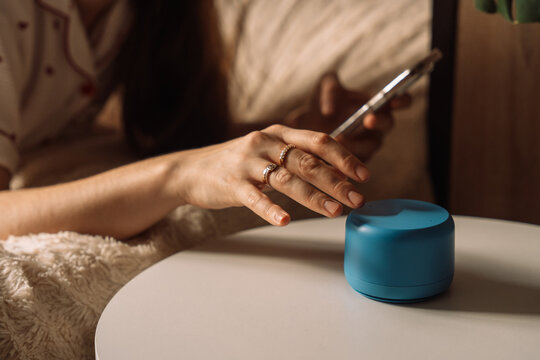 Hand reaching to interact with blue AI smart speaker. High quality photo