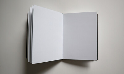 An open sketchbook showing two blank white pages on a neutral light gray background. Ideal for...