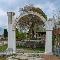 Ancient marble archway and columns at the Izmir Agora of Smyrna, a historic archaeological site in Izmir, Turkey, under a cloudy sky