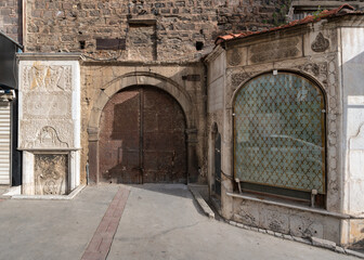 Historic facade of 7 Uyuyanlar Cesmesi, Seven Sleepers Fountain, with ornate carvings and a rustic arched door in Konak, Izmir, Turkey