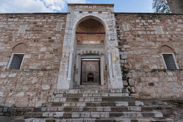 Ulu Camii Mosque, Manisa, Turkey. Grand stone facade with an ornate arched entrance, steps, and traditional windows under a blue sky