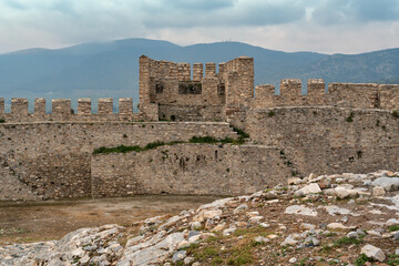 Ancient stone walls and battlements of Ayasuluk Castle, Selcuk, Izmir, Turkey. The historic fortress stands against misty mountains under a cloudy sky
