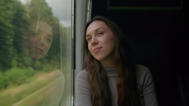 Young woman enjoys a scenic train journey through lush green landscapes
